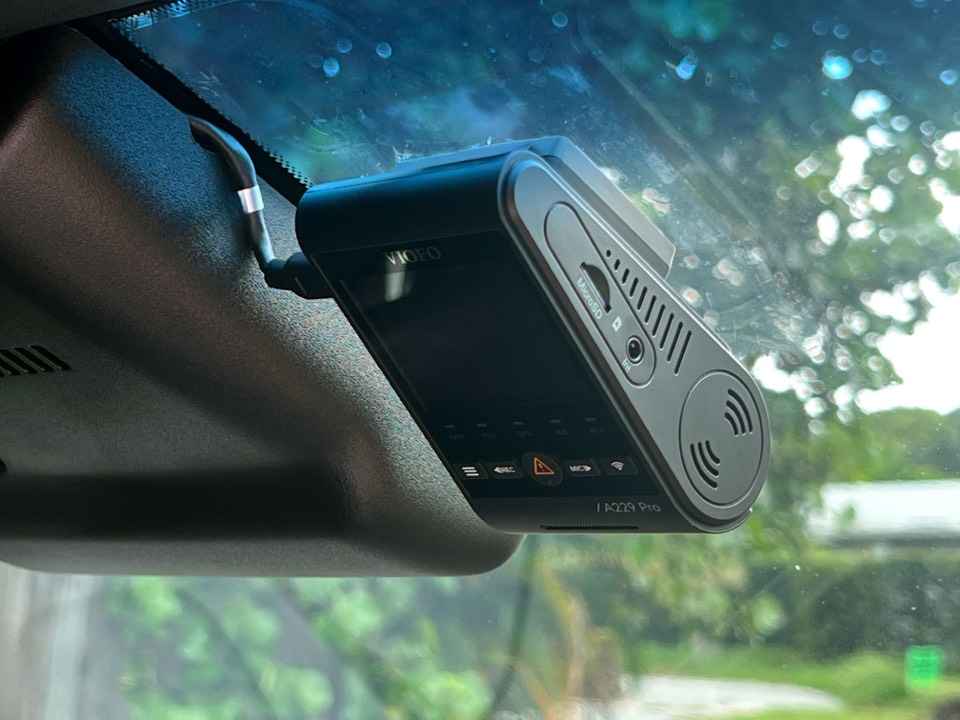 A Viofo A229 Pro dash camera installed behind a rearview mirror, nearly invisible from the driver's seat